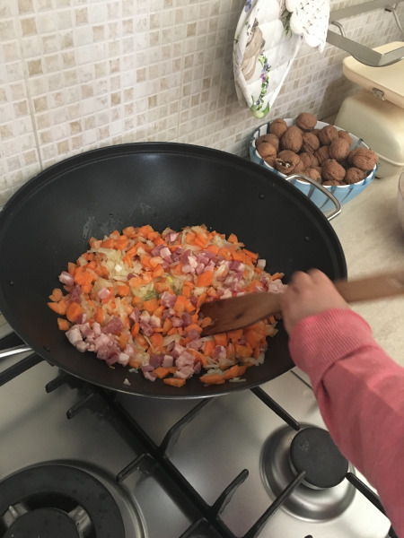 bambina che mescola soffritto di carote e cipolla