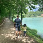 papà tiene per mano bambina mentre cammina sulle rive del lago