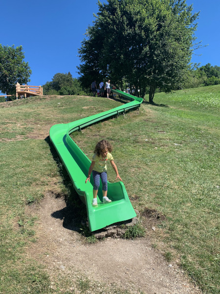 bambina su lungo scivolo verde