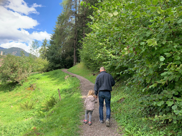 papà e bambina camminano su sentiero di montagna