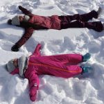 mamma e figlia sdraiate sulla neve