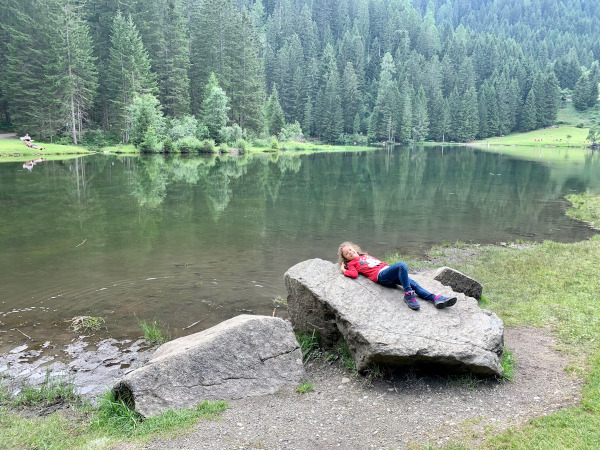 bambina sdraiata su sasso in riva al lago